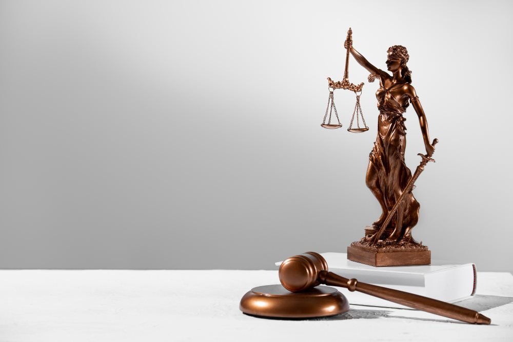Estatua de la justicia y mazo de juez sobre un escritorio
