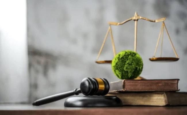 Balanza de la justicia, mazo y esfera verde sobre libros