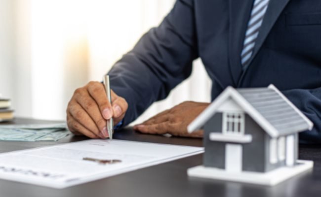 Firma de contrato junto a una maqueta de casa